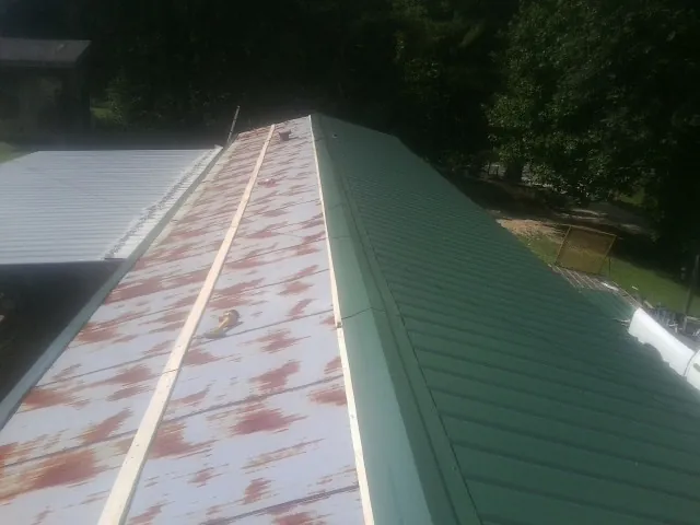 Old rusted panels beside newly installed green metal roofing — Wind Damage Roof Repair by Roofing Brothers in New Durham
