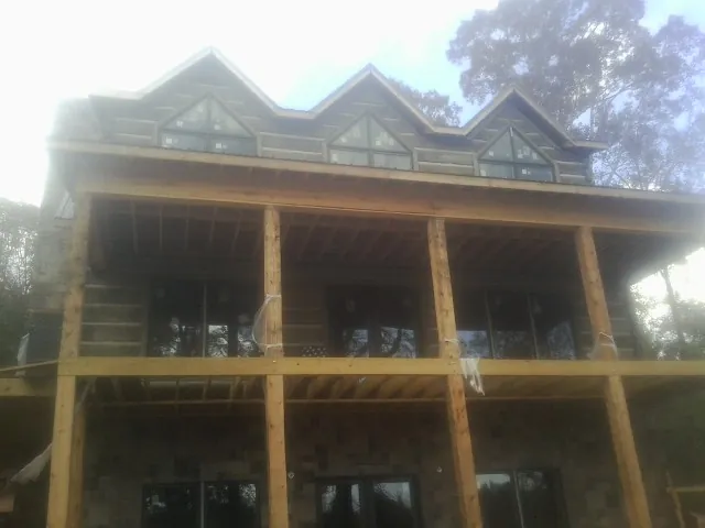 Dormers and porch framing on a large log home under construction — Roof Coating work by our crew in New Durham