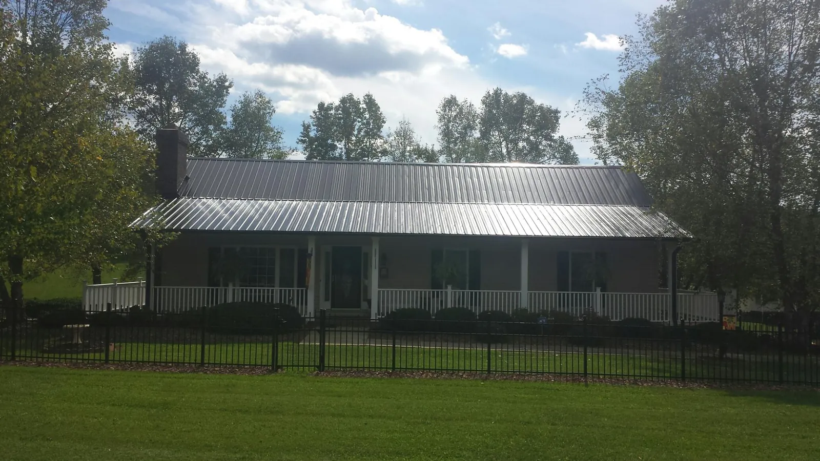 Gray metal roof on a brick ranch with a full width front porch — Gutter Guard Installation work by our crew in New Durham