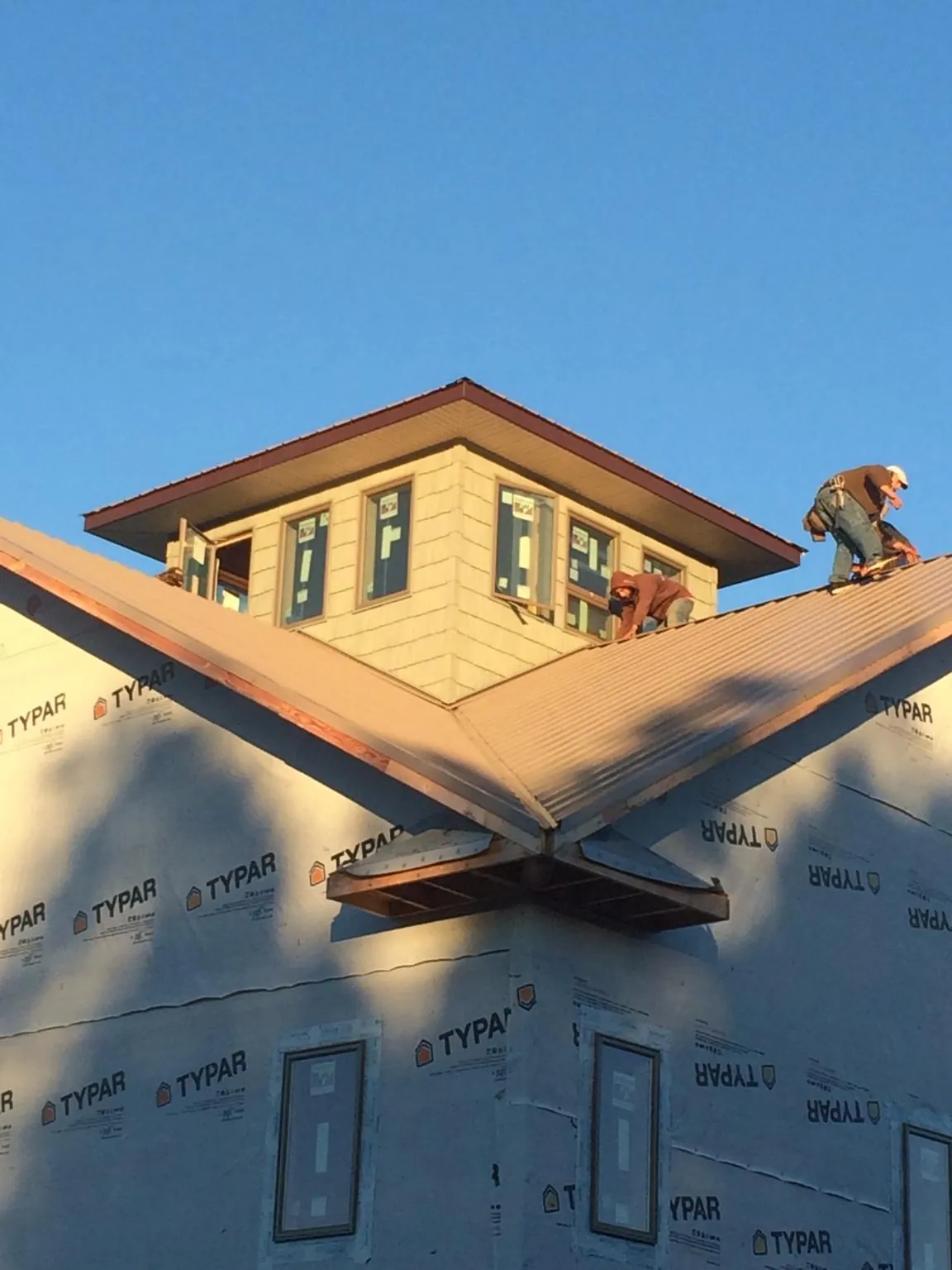 Roofers working around a rooftop cupola on a new metal roof at sunset — Roof Waterproofing in New Durham by Roofing Brothers